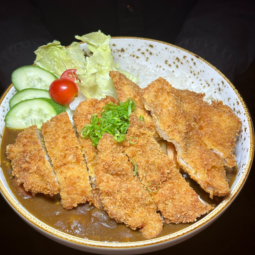 Sliced golden chicken katsu over curry, with rice, lettuce, cucumber and tomato at RAYU